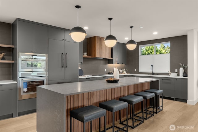 238 4th Ave Unit 100, Kirkland, WA 98033 - kitchen featuring stainless steel double oven, tasteful backsplash, gray cabinetry, a center island, and recessed lighting