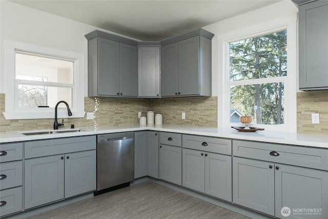 kitchen featuring sink, gray cabinetry, tasteful backsplash, wood-type flooring, and stainless steel dishwasher