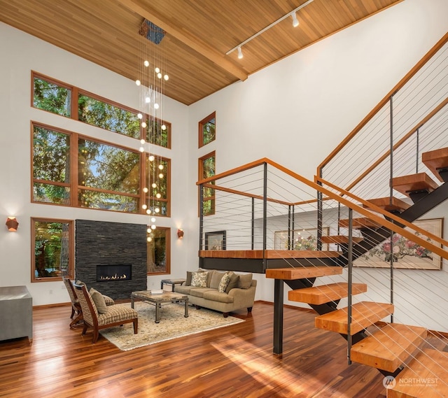 living room with hardwood / wood-style flooring, a towering ceiling, wooden ceiling, and a fireplace