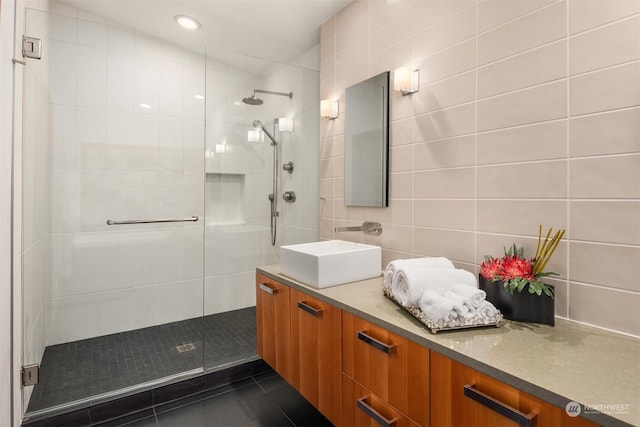 bathroom with decorative backsplash, vanity, tile walls, and a tile shower
