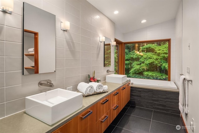 bathroom featuring tile patterned flooring, tile walls, vanity, a bath, and vaulted ceiling