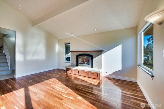 unfurnished living room with high vaulted ceiling, dark hardwood / wood-style flooring, a brick fireplace, wooden ceiling, and beamed ceiling