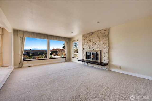 unfurnished living room featuring a stone fireplace and carpet