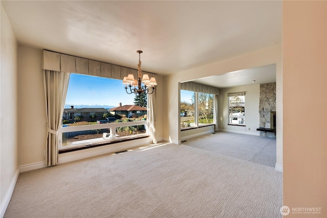 unfurnished dining area with an inviting chandelier, a fireplace, and light carpet