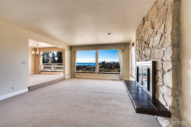 unfurnished living room featuring carpet floors, a chandelier, and a fireplace