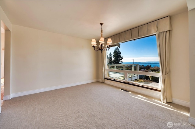 carpeted empty room featuring an inviting chandelier