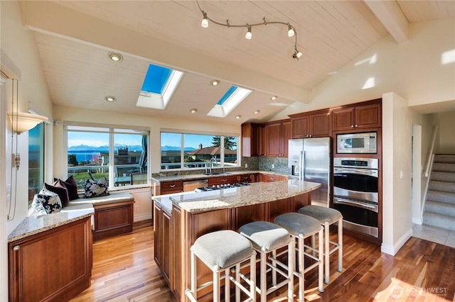 kitchen featuring light stone countertops, appliances with stainless steel finishes, a center island, and a breakfast bar