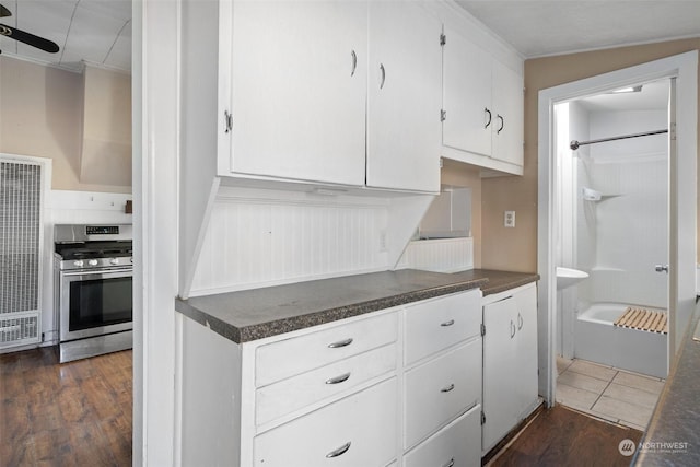 kitchen featuring dark countertops, white cabinets, dark wood finished floors, and gas stove