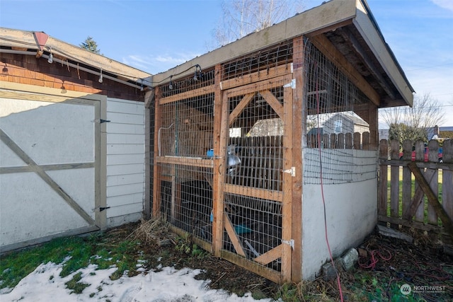 snow covered structure featuring an outbuilding and fence