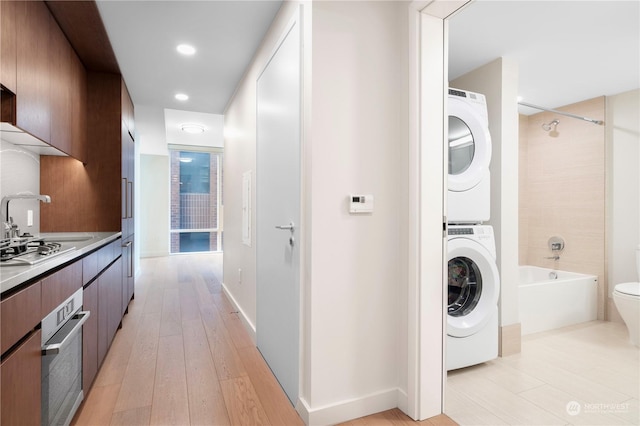 washroom featuring stacked washer and clothes dryer and light wood-type flooring