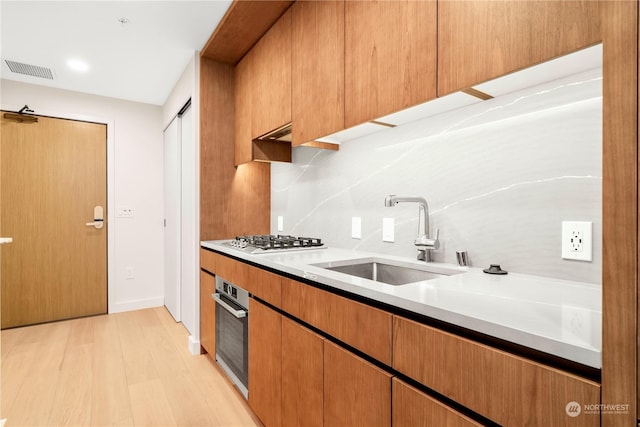 kitchen featuring stainless steel appliances, tasteful backsplash, sink, and light hardwood / wood-style floors