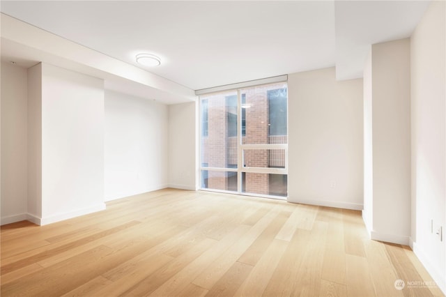 unfurnished room featuring expansive windows and light hardwood / wood-style floors