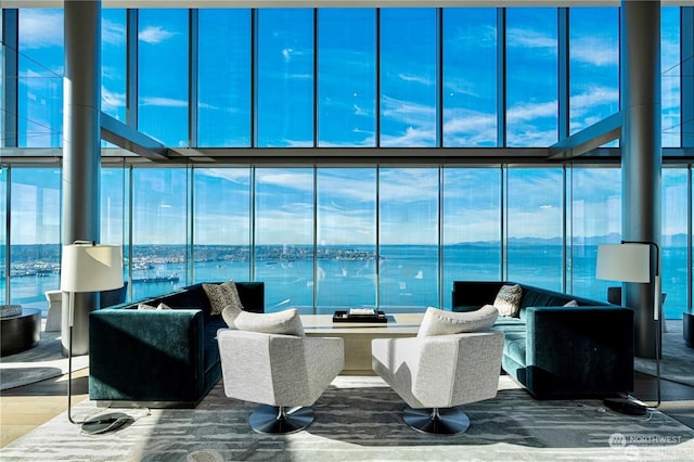 living room with expansive windows, a water view, and hardwood / wood-style flooring