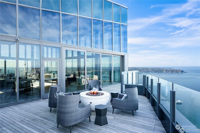 wooden deck with a water view and a fire pit