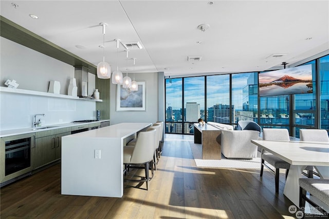 kitchen with decorative light fixtures, a center island, dark hardwood / wood-style flooring, expansive windows, and beverage cooler