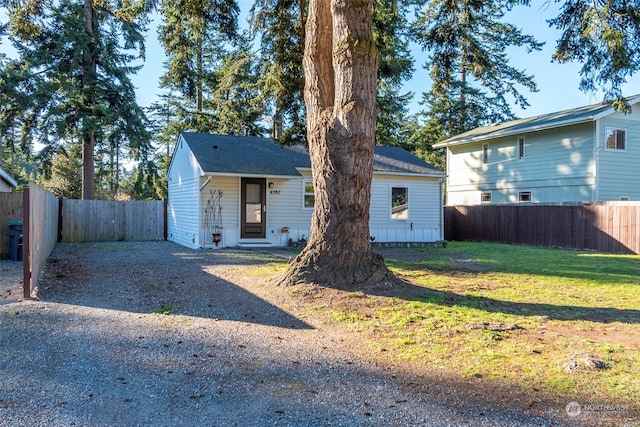 view of front of home featuring gravel driveway, fence private yard, and a front lawn