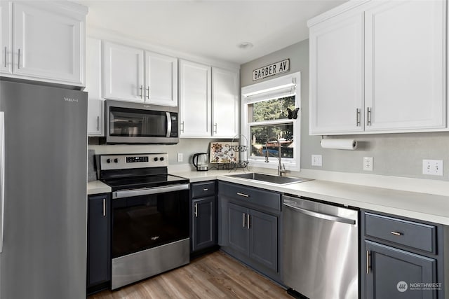 kitchen featuring white cabinets, stainless steel appliances, a sink, and light countertops