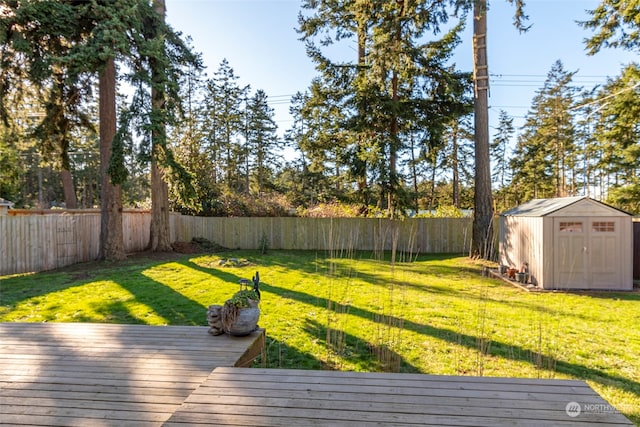 view of yard with an outbuilding, a shed, a fenced backyard, and a deck