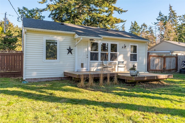 rear view of house featuring a deck, a lawn, and fence