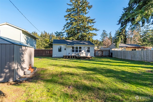 rear view of property featuring a fenced backyard, a deck, a yard, a shed, and an outdoor structure