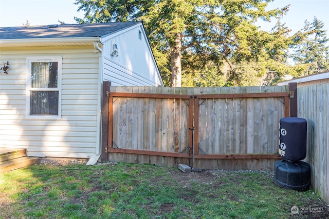 view of side of home featuring fence, a lawn, and roof with shingles