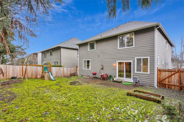 back of house featuring an outdoor fire pit, a yard, and a playground