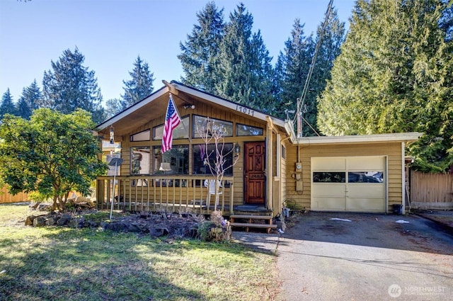 view of front of property with driveway, an attached garage, fence, and a front yard