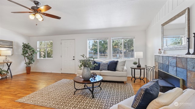 living room featuring a tiled fireplace, a wealth of natural light, and light wood-type flooring