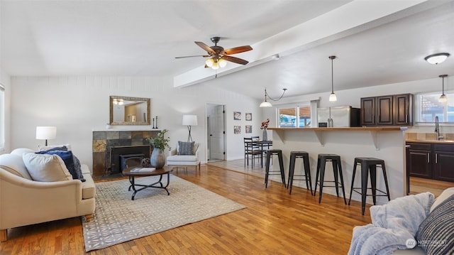 living room with vaulted ceiling with beams, sink, ceiling fan, and light wood-type flooring