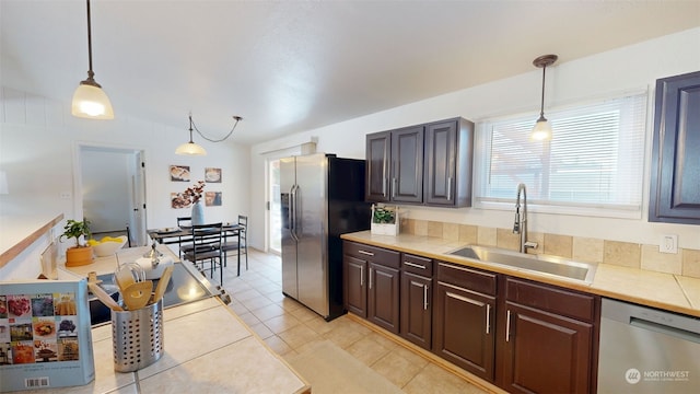 kitchen featuring dark brown cabinetry, appliances with stainless steel finishes, decorative light fixtures, and sink