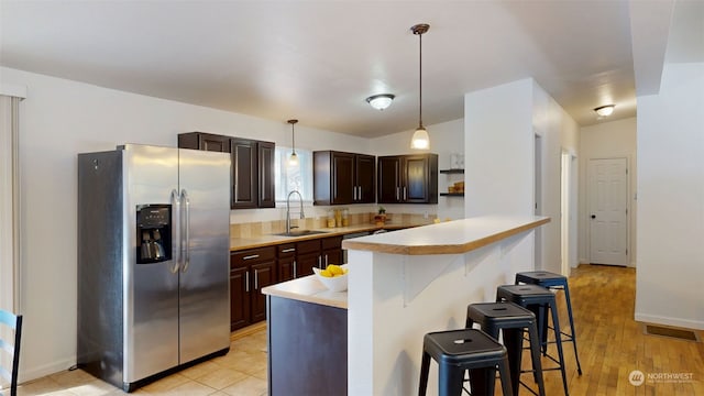 kitchen featuring pendant lighting, stainless steel fridge, sink, and a breakfast bar area