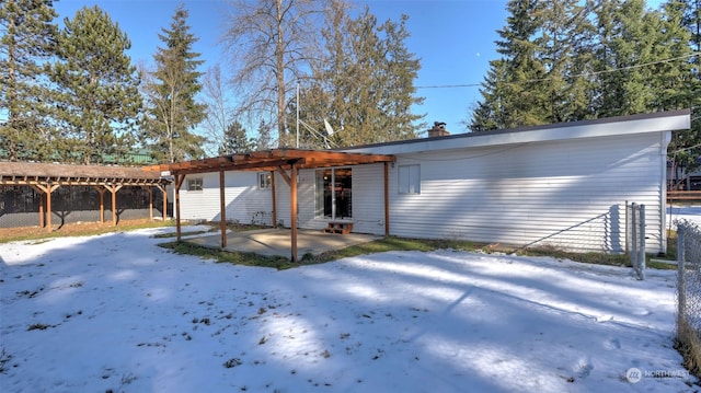 snow covered rear of property with a patio area