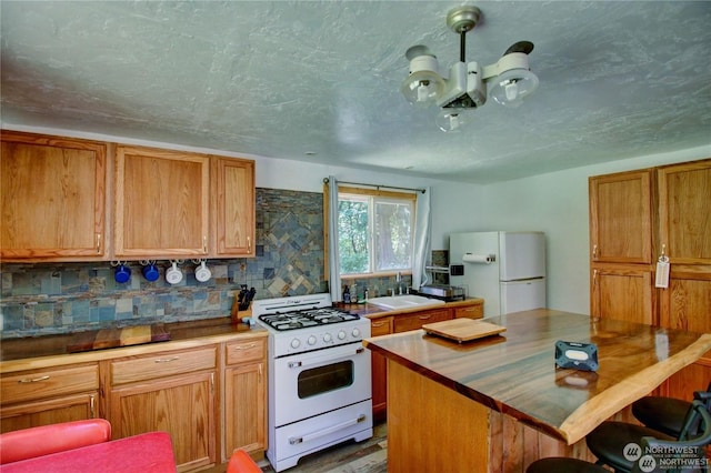 kitchen featuring a kitchen island, butcher block counters, sink, decorative backsplash, and white appliances