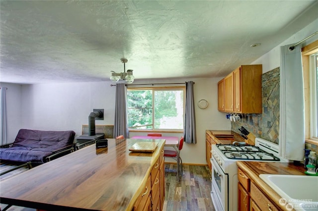 kitchen with hardwood / wood-style floors, tasteful backsplash, sink, wooden counters, and white range with gas stovetop