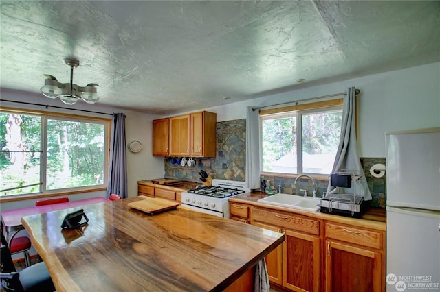 kitchen featuring wood counters, sink, a chandelier, white appliances, and decorative backsplash