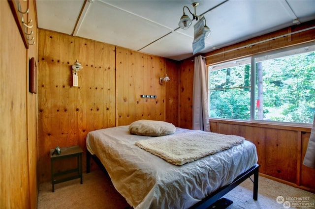 carpeted bedroom featuring wood walls