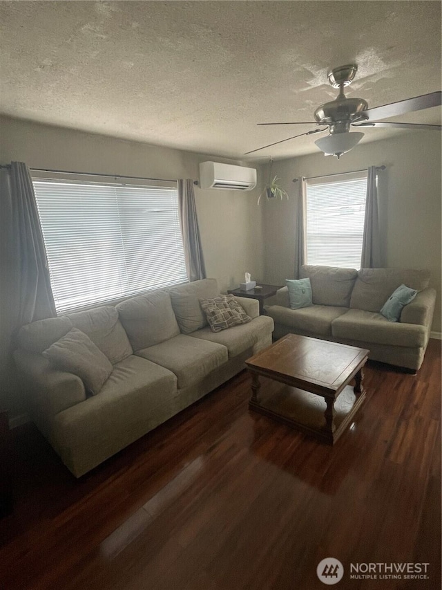 living room featuring a textured ceiling, dark wood-style flooring, a wall mounted air conditioner, and a ceiling fan