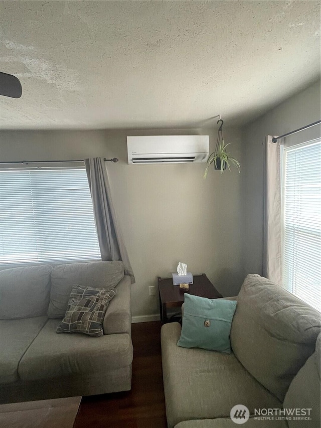 living room featuring baseboards, dark wood finished floors, a textured ceiling, and a wall mounted air conditioner