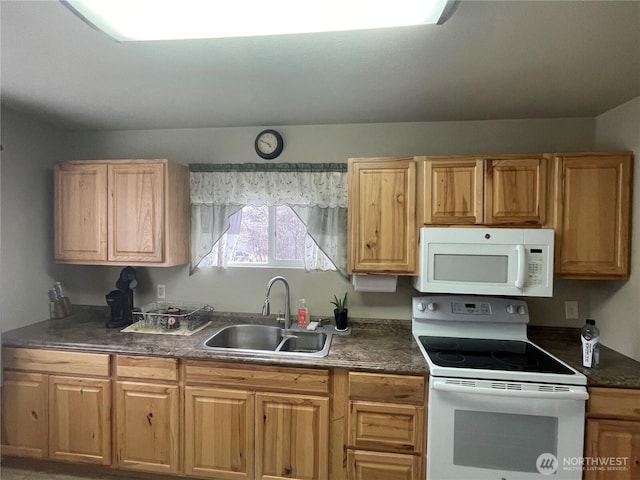 kitchen with dark countertops, white appliances, and a sink