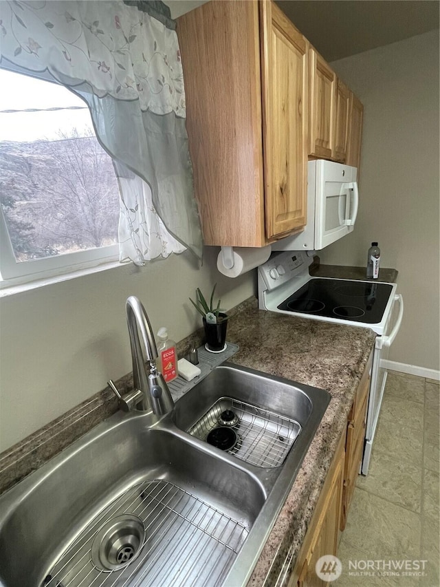 kitchen with dark countertops, white appliances, a sink, and baseboards