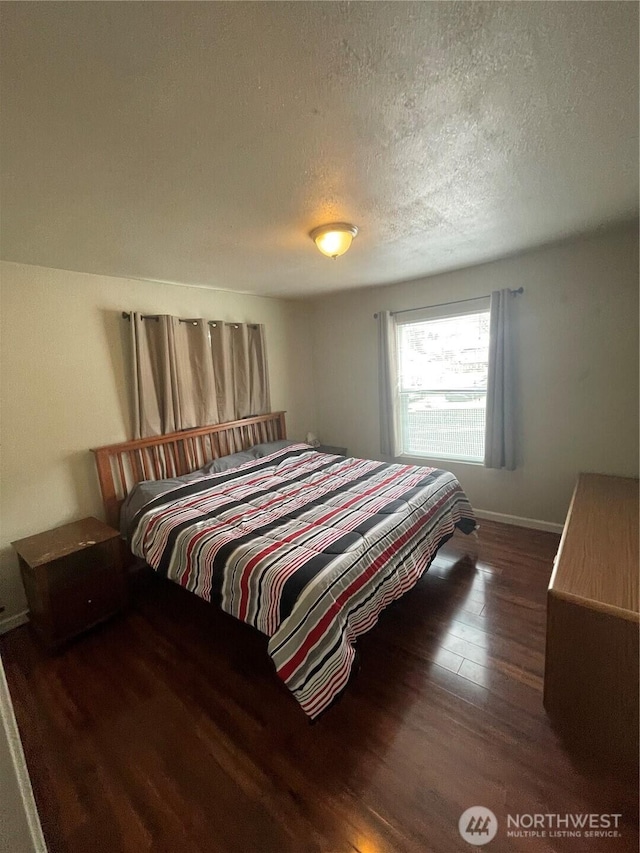 bedroom with baseboards, dark wood finished floors, and a textured ceiling