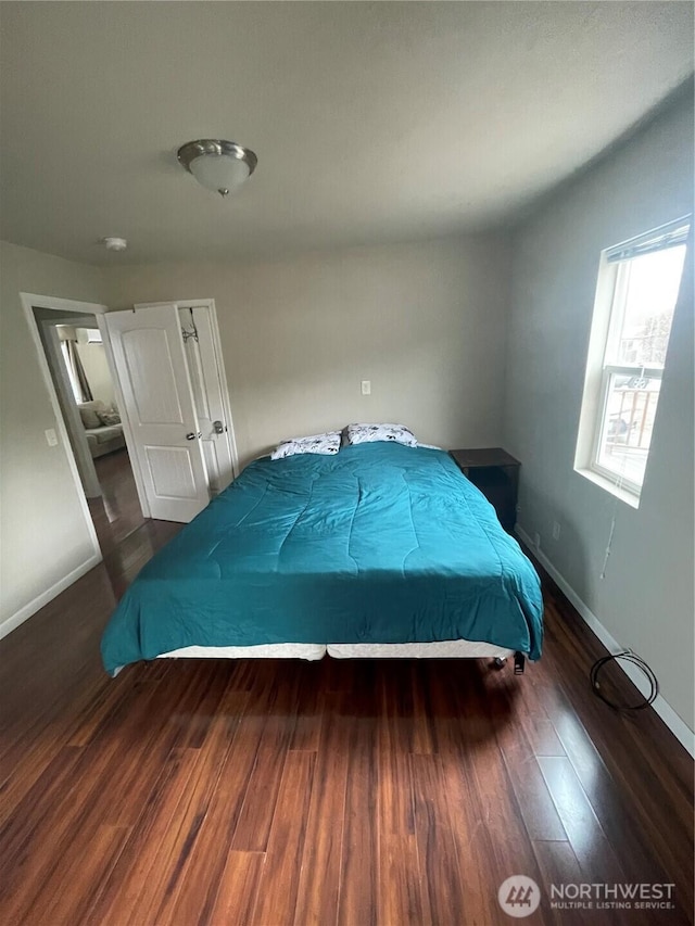 bedroom with dark wood-style flooring and baseboards