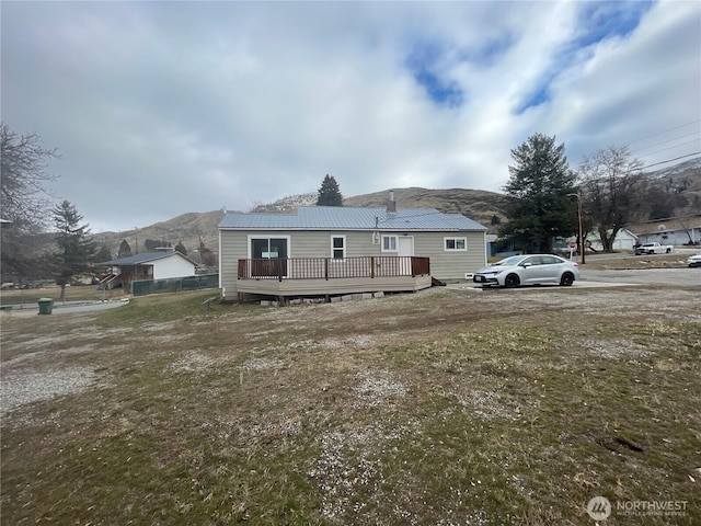 back of property with a deck with mountain view and metal roof