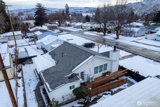 snowy aerial view featuring a residential view and a mountain view