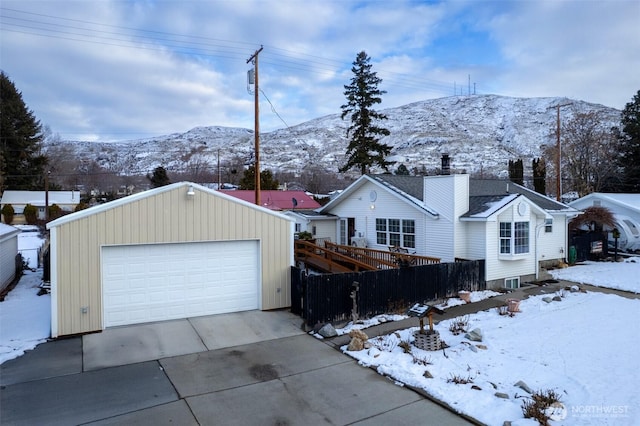 ranch-style house featuring a chimney, fence, a detached garage, and an outdoor structure