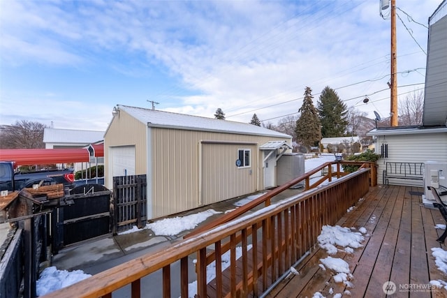 snow covered deck featuring a garage and an outbuilding