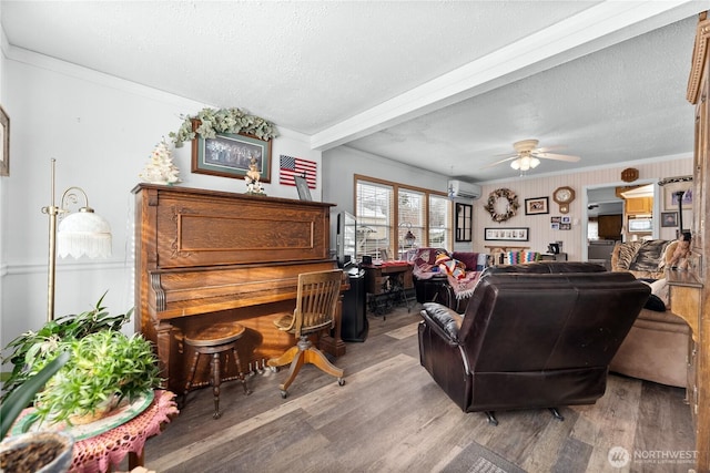 living area featuring ornamental molding, a wall mounted air conditioner, a textured ceiling, and wood finished floors