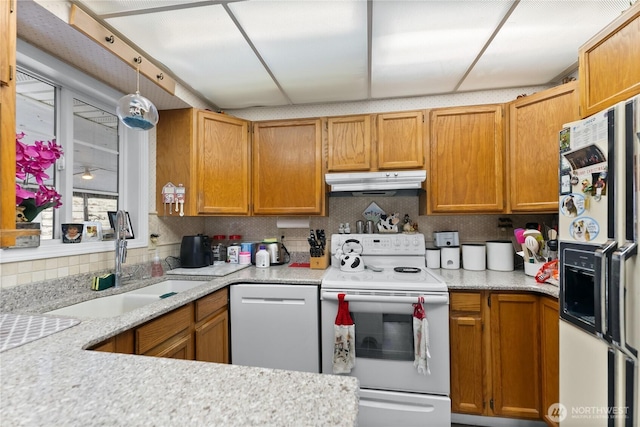 kitchen featuring white appliances, under cabinet range hood, light countertops, and a sink