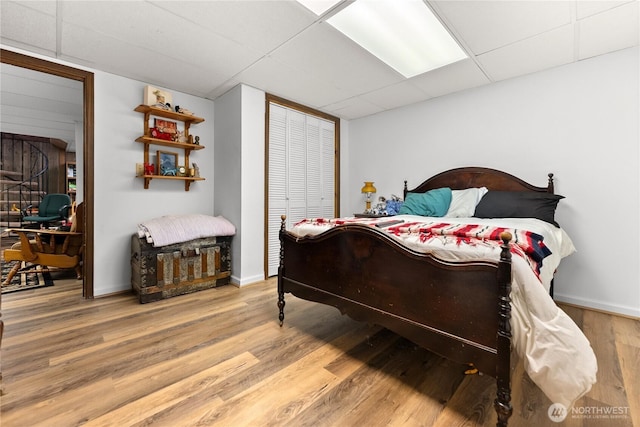 bedroom with a paneled ceiling, baseboards, and wood finished floors