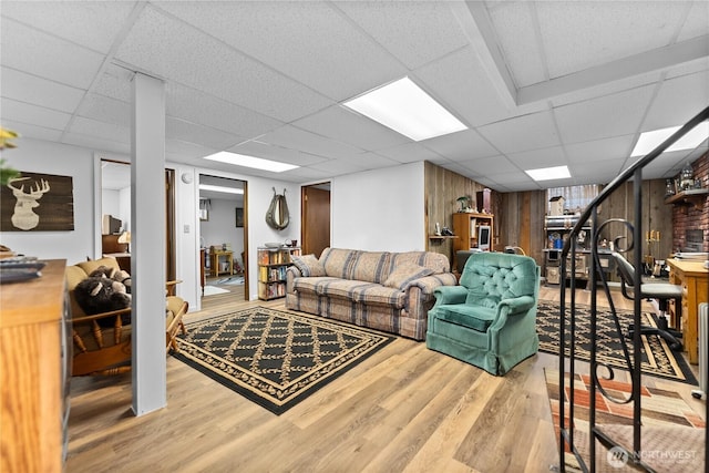 living area with a paneled ceiling and wood finished floors